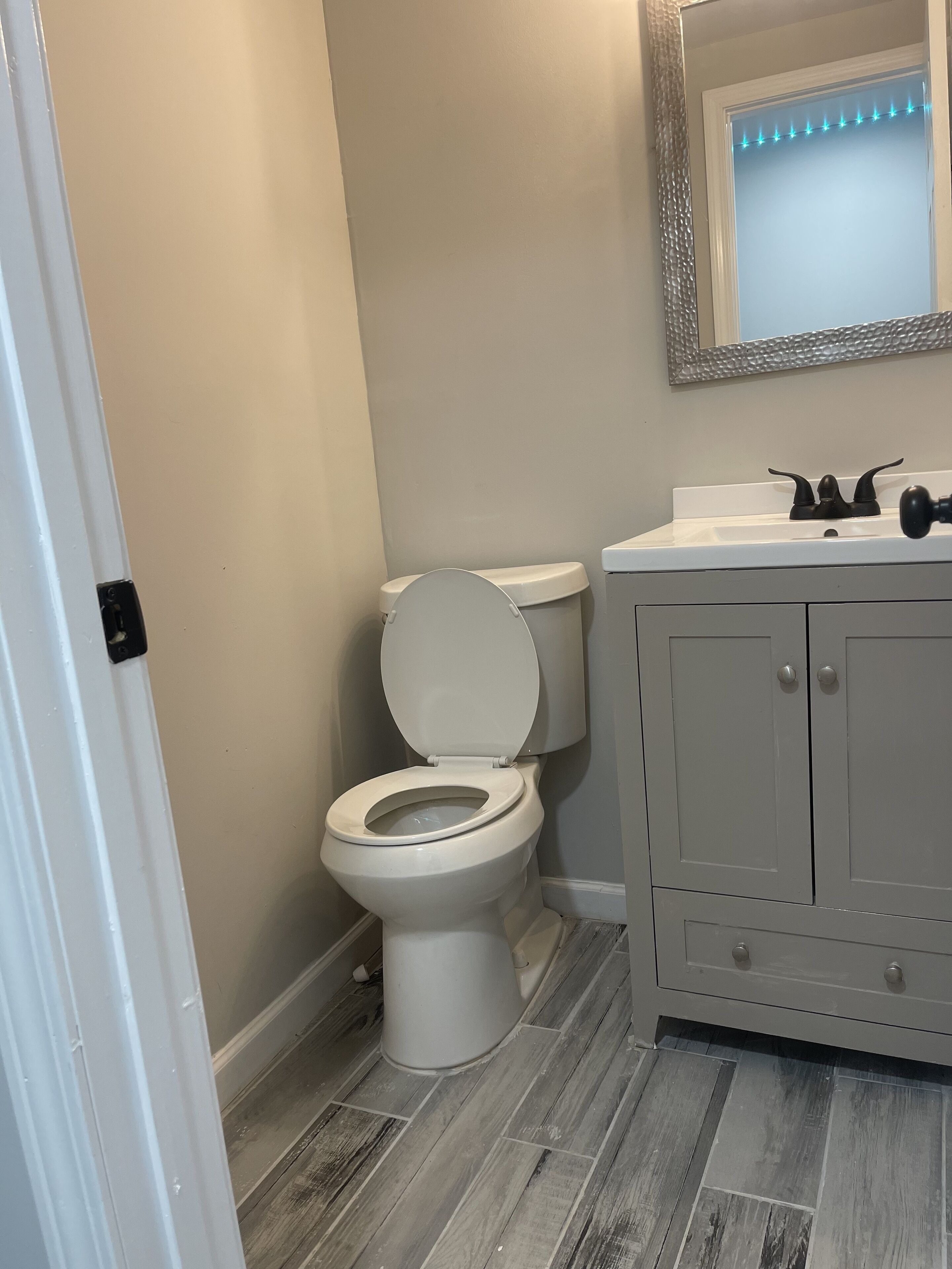 A bathroom with a toilet, sink, and mirror.