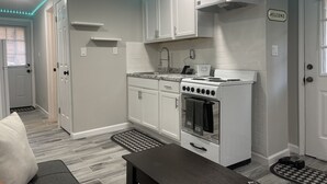 Cocina compacta con armarios blancos, estufa y pileta. Luces LED color turquesa a lo largo del borde del techo.