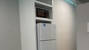 Una cocina con un refrigerador blanco, un microondas y luces LED a lo largo del techo.