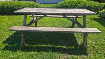 Una mesa de picnic de madera con bancos en un área cubierta de césped.