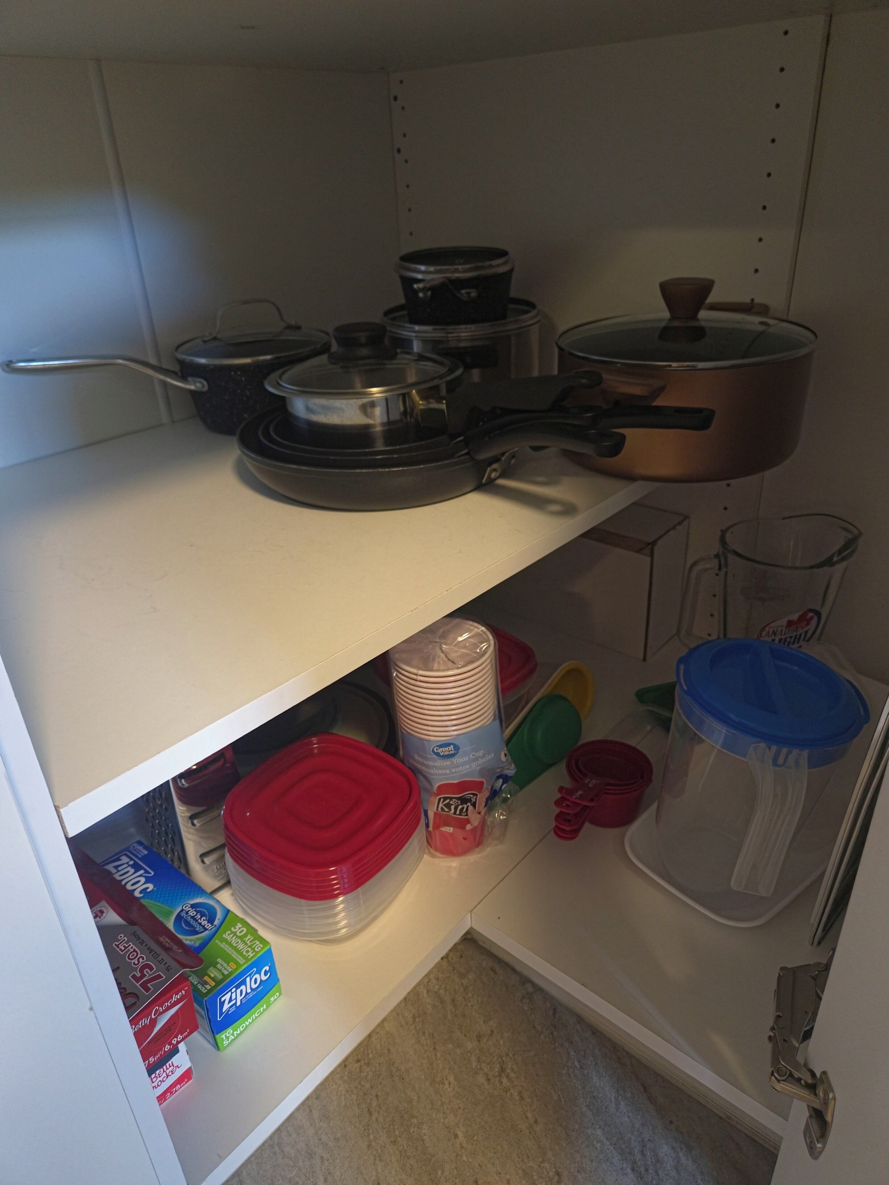 Una cocina con varias ollas y sartenes sobre la encimera, recipientes de almacenamiento en los estantes y una cafetera a la derecha.