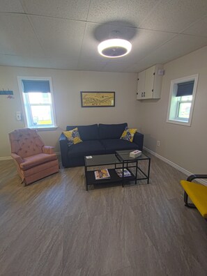 Ein Wohnzimmer mit Sofa, Sessel, Couchtisch und einer Karte an der Wand.