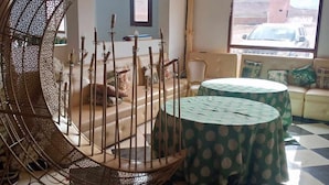 A room with a checkered floor, a round table with a green tablecloth, a sofa, and a decorative metal spiral structure. - Hôtel et Restaurant Kinan (Amersid)