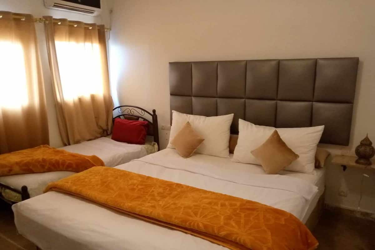 A hotel room with two beds, each with a headboard and multiple pillows.