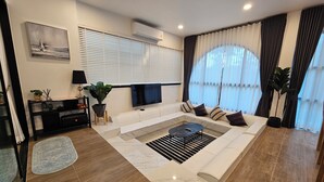 A modern living room with a sofa, TV, and a coffee table. - Live with passion pool villa (Pak Chong)