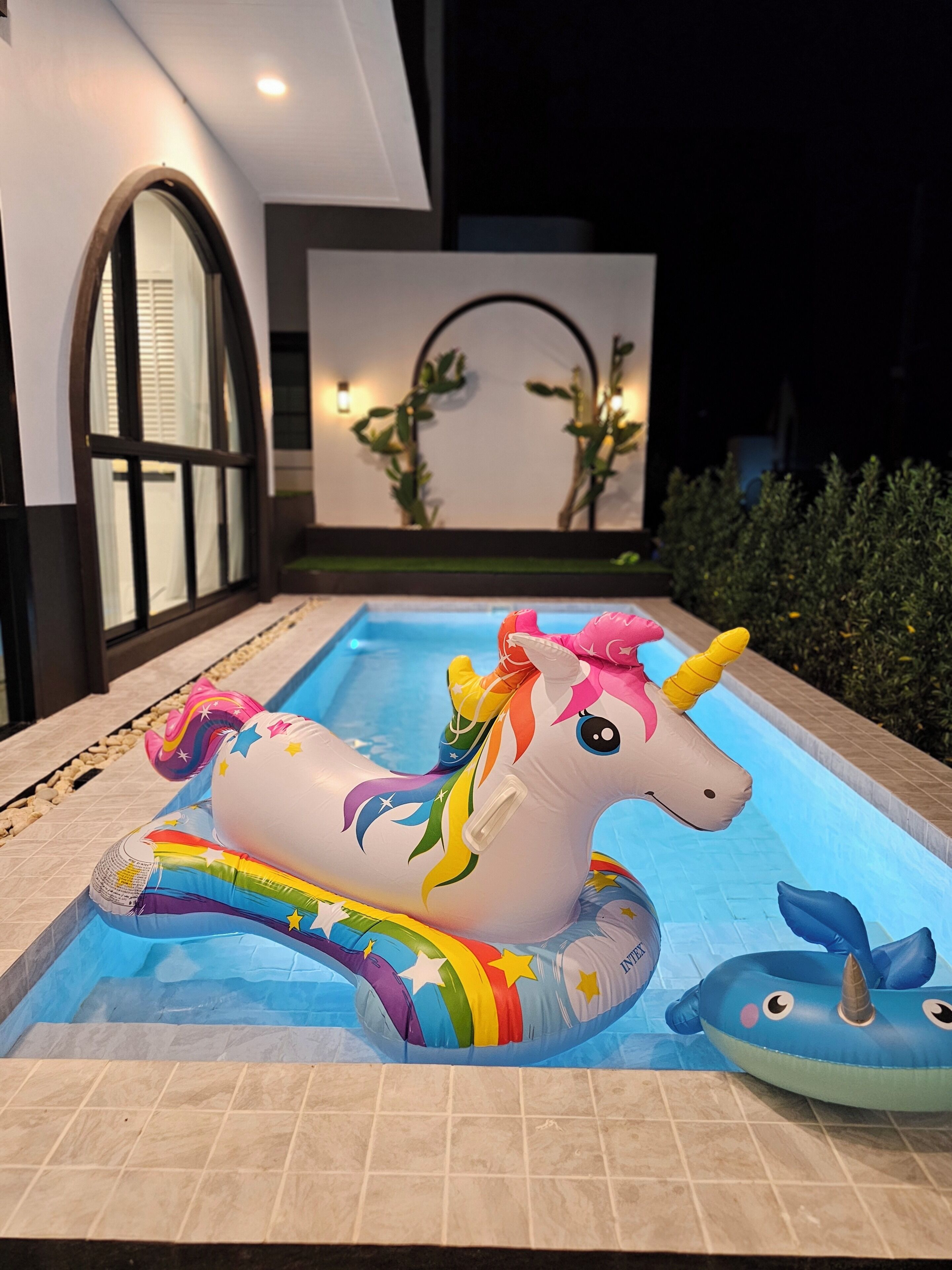 A swimming pool with inflatable unicorn and whale toys.