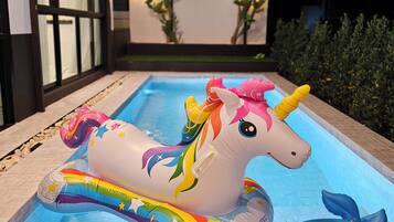 A swimming pool with inflatable unicorn and whale toys.