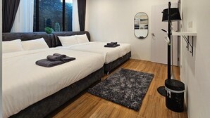 A modern hotel room with a large bed, a smaller bed, a mirror, a black floor lamp, and a black trash bin. - Live with passion pool villa (Pak Chong)