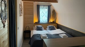 A bedroom with a bed, a chair, a window with curtains, and a decorative wall piece. - Calm Resort Hertelend (Magyarhertelend)