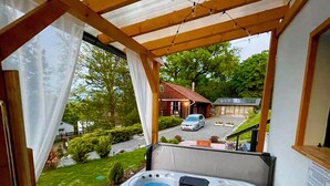 A hot tub under a wooden pergola with a view of a house and a car in the background. - Calm Resort Hertelend (Magyarhertelend)