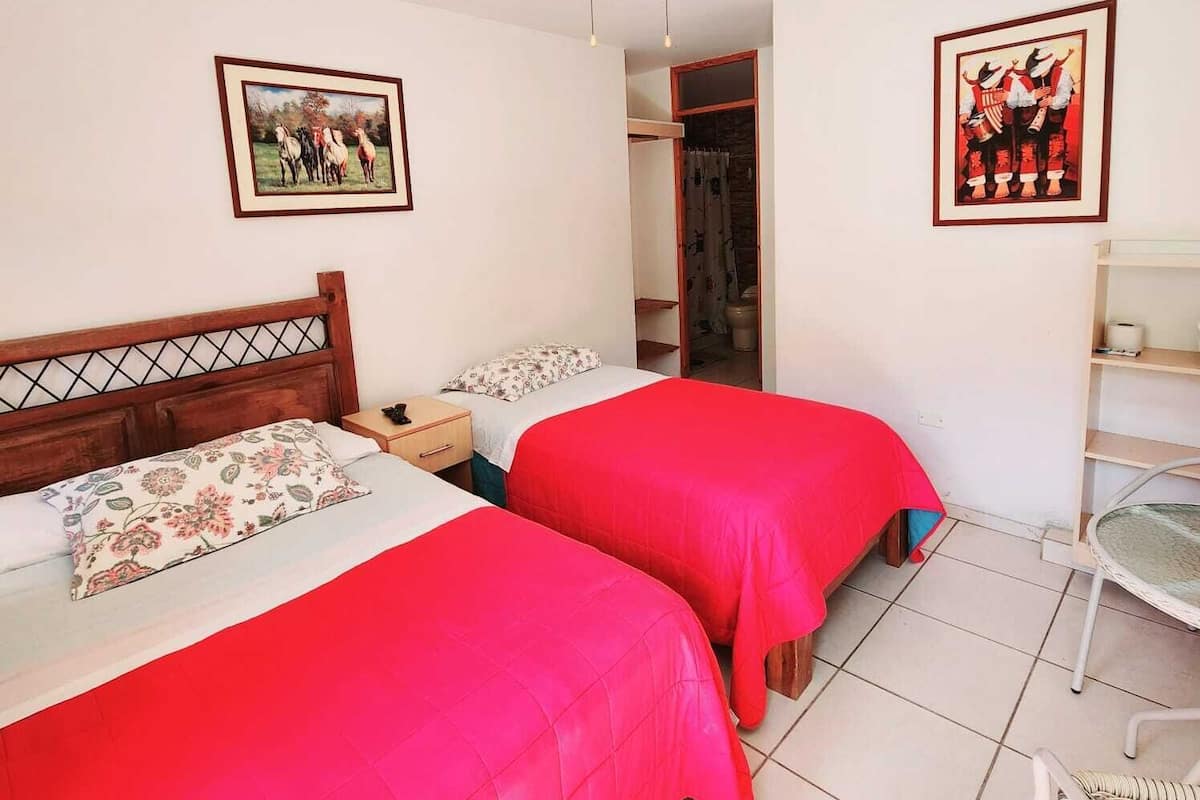 Un dormitorio con dos camas, un ventilador de techo y dos cuadros en las paredes.