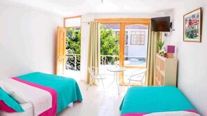 Quarto de hotel com duas camas, varanda, televisão e uma pequena mesa.