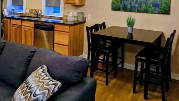 Una cocina moderna con armarios de madera, un comedor con mesa y sillas, y una sala de estar con sofá.