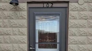 Una puerta con el número 102, un panel de vidrio y un felpudo.