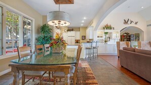 Une cuisine spacieuse avec un coin repas, comprenant une table en verre, des chaises en bois et une grande plante servant de centre de table.