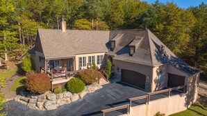 Une grande maison de plain-pied dotée d’un patio couvert, d’un garage et d’un mur de soutènement en pierre.