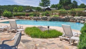 Une piscine avec des chaises longues et une terrasse en pierre.