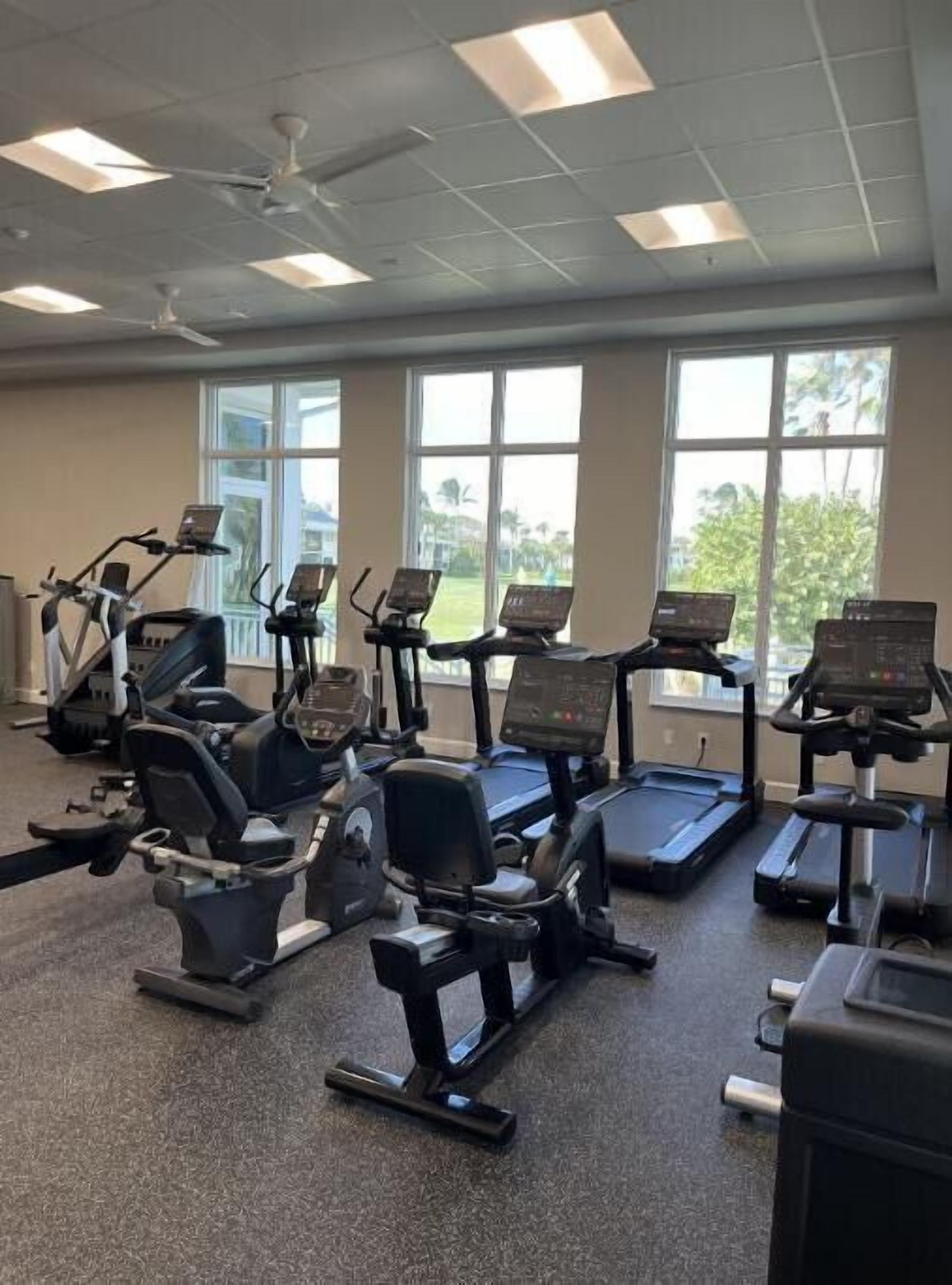 Une salle de sport équipée de tapis de course, d’appareils elliptiques et de vélos d’appartement.