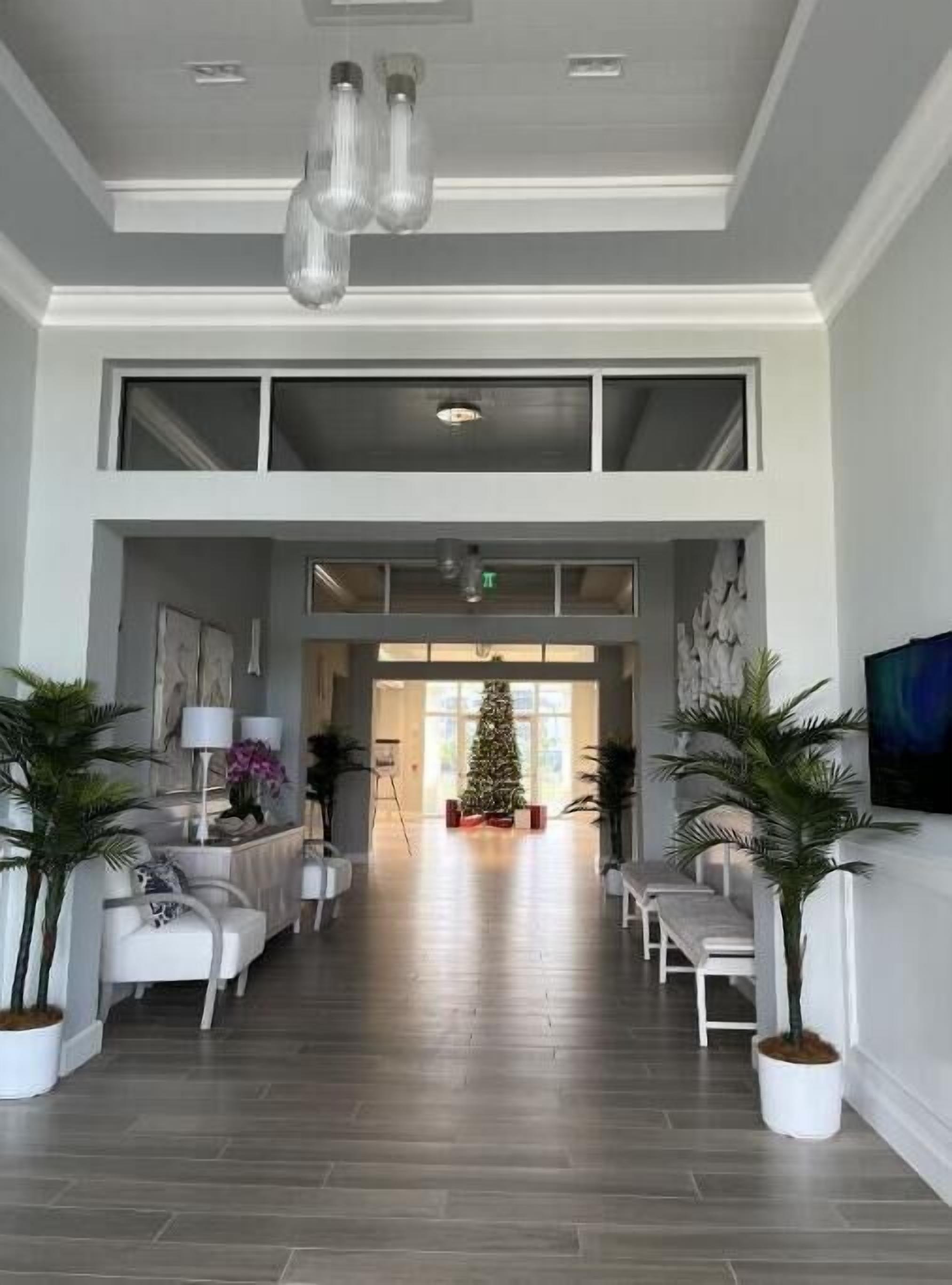 A spacious lobby with a high ceiling, a central Christmas tree, and a modern design with white furniture and potted plants.