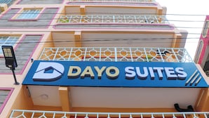 Un letrero de hotel con el nombre "Dayo Suites" y un diseño de ventana geométrico.