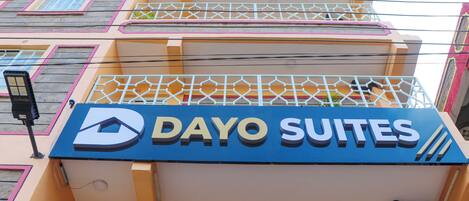 A hotel sign with the name "Dayo Suites" and a geometric window design.