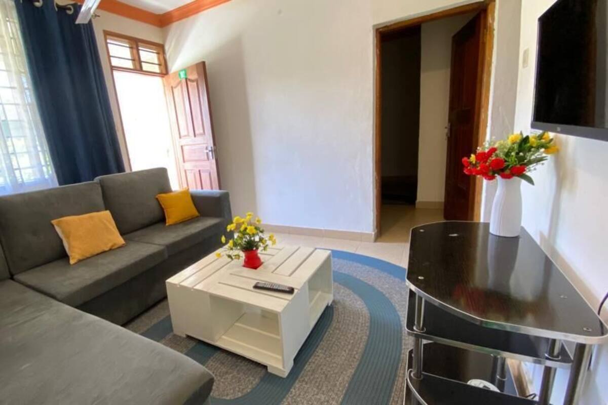 A living room with a grey sofa, a white coffee table, and a TV on a stand.