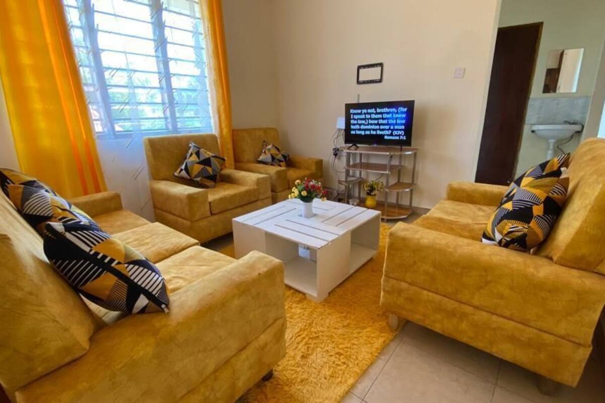 A living room with yellow sofas, a white coffee table, and a TV on a stand.