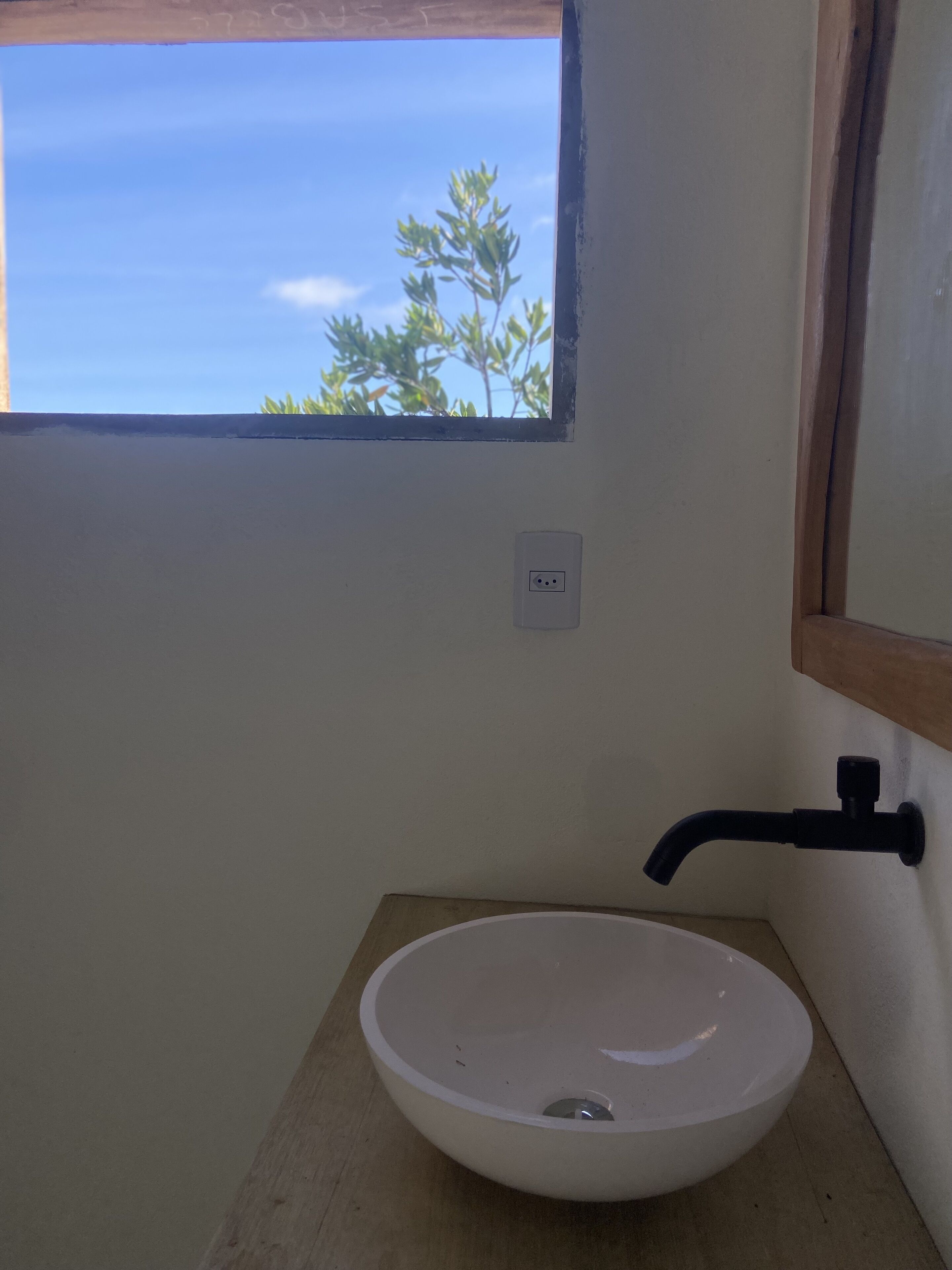 Un bagno con un lavandino bianco, una finestra e un piano in legno.
