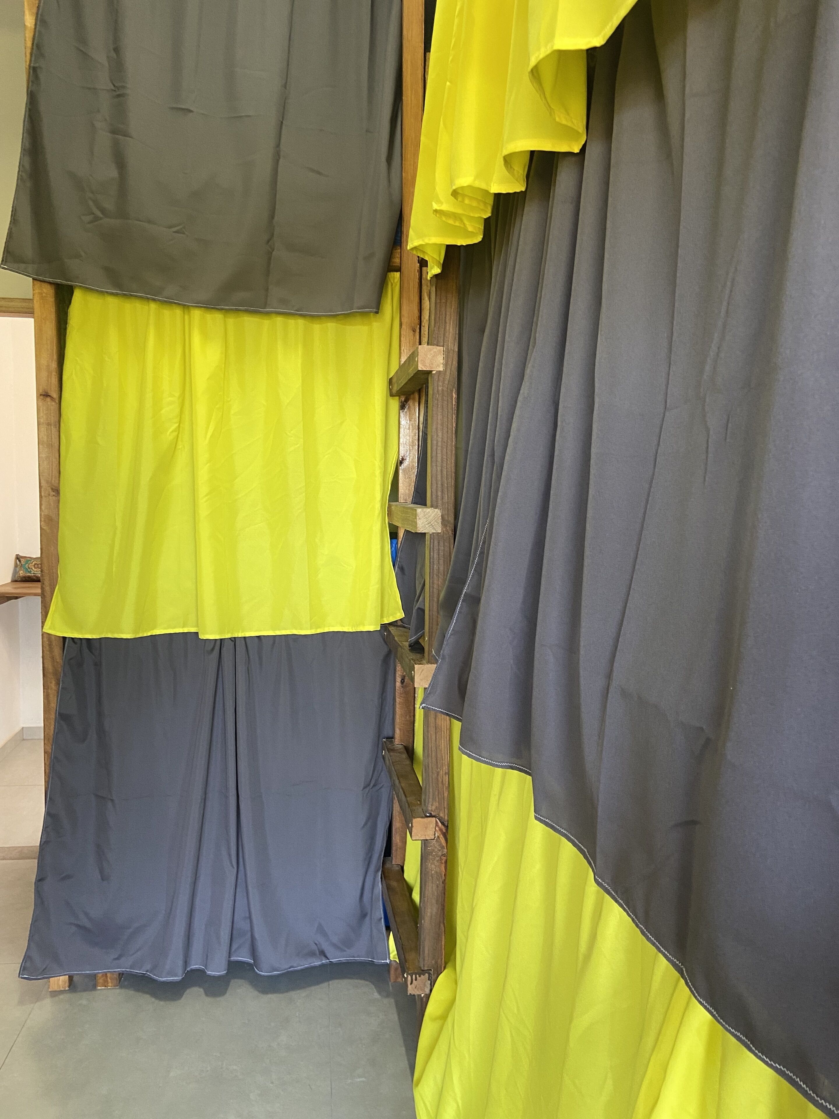 Una habitación con una escalera de madera y cortinas grises y amarillas.
