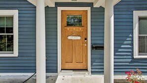 A wooden front door with a sign that reads "STAY AWAY" and a mailbox to the right.
