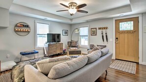 A modern living room with a ceiling fan, a sofa, a TV, and a bookshelf.