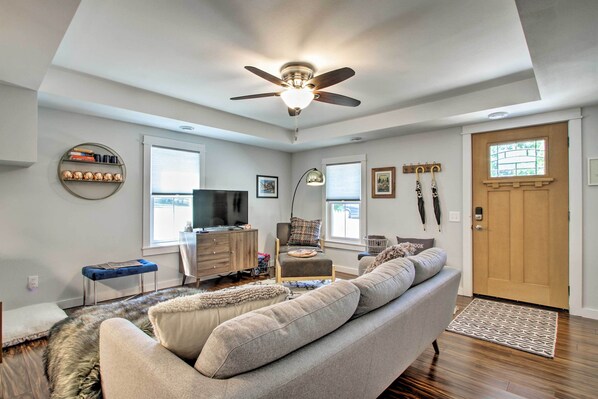 A modern living room with a ceiling fan, a sofa, a TV, and a bookshelf.