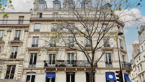 A multi-story building with balconies and a tree in front. - Superb apartment with AC - Beaubourg Le Marais (Paris)