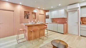 A modern kitchen with a central island, bar stools, and a dining area with a glass table. - Superb apartment with AC - Beaubourg Le Marais (Paris)