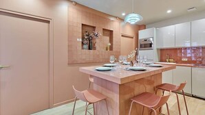 A modern kitchen with a central island, white cabinets, and a pink backsplash. - Superb apartment with AC - Beaubourg Le Marais (Paris)