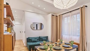A modern dining area with a wooden table set for four, a teal sofa, and a large mirror on the wall. - Charming & Modern apartment  center of Paris (Paris)