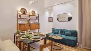 A modern living room with a dining area, a teal sofa, and a wooden bookshelf. - Charming & Modern apartment  center of Paris (Paris)