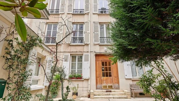 A multi-story building with balconies, a wooden door, and potted plants. - Charming & Modern apartment  center of Paris (Paris)