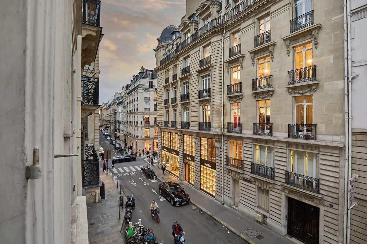 Une vue de rue d’un immeuble parisien à plusieurs étages, doté de grandes fenêtres et de balcons.