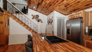 A kitchen with a wooden countertop, stainless steel refrigerator, and a wooden staircase. - Red River Ranch Retreat- HOT TUB, Views, Pond- Near RRG (Frenchburg)