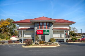 Un edificio de dos pisos con techo rojo y un cartel que dice Red Roof Inn y Hometown Studios.