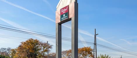 Un panneau « Red Roof Inn » avec un symbole représentant une maison, indiquant la possibilité de séjourner dans un logement chez l’habitant.