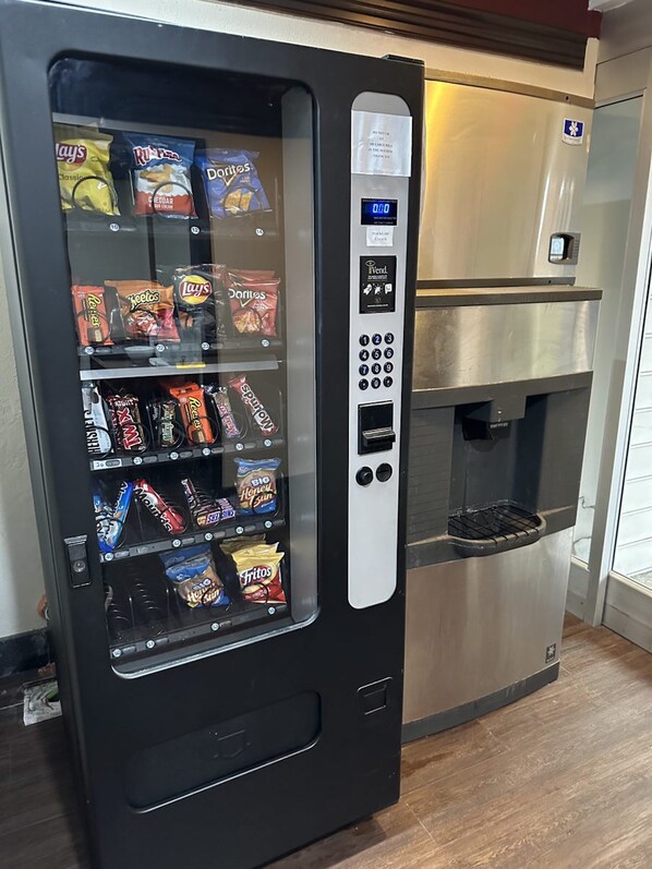 Una máquina expendedora con snacks como Lay's, Ruffles y Doritos, y una máquina de café a su lado.