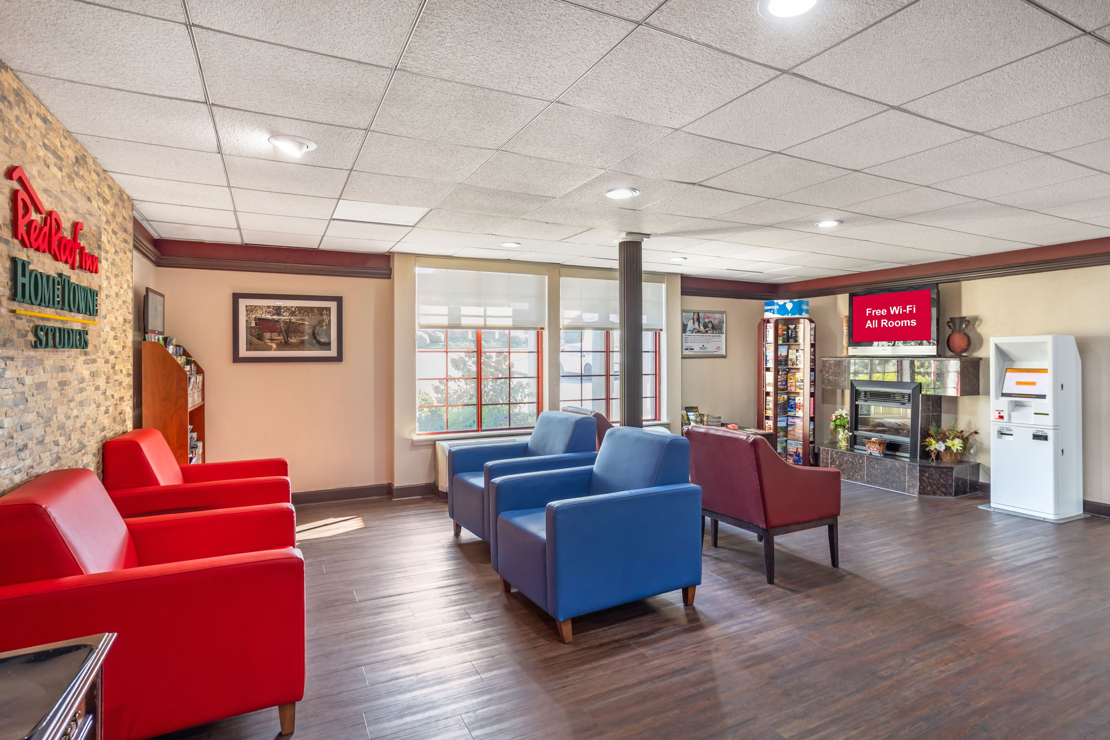 A reception area with red and blue chairs, a fireplace, and a sign indicating free Wi-Fi.