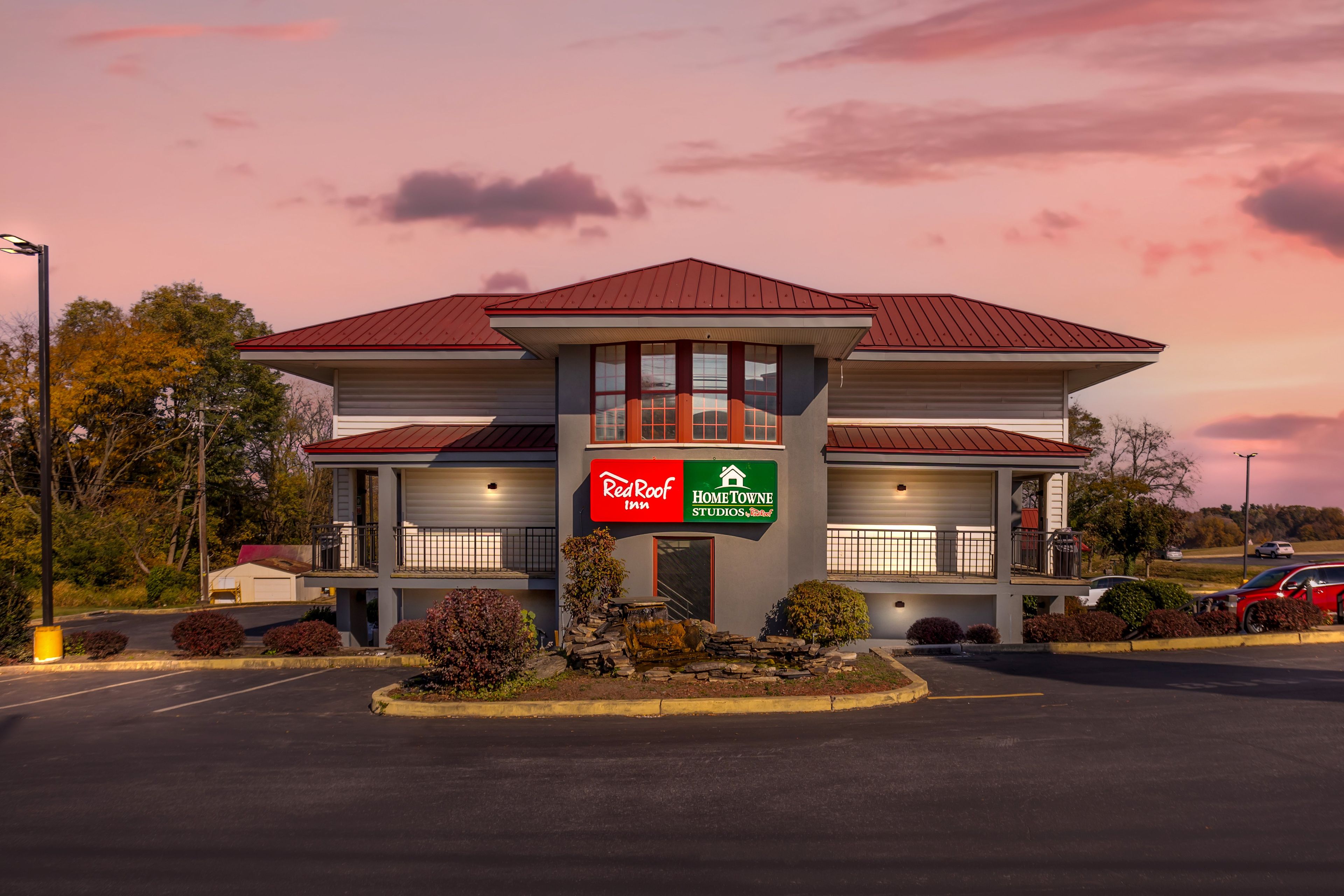 A two-story building with a red roof and a sign for Red Roof Inn and HomeTowne Studios.