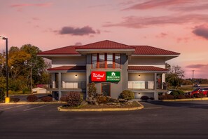 Un edificio de dos plantas con techo rojo y un cartel que anuncia Red Roof Inn y HomeTowne Studios.