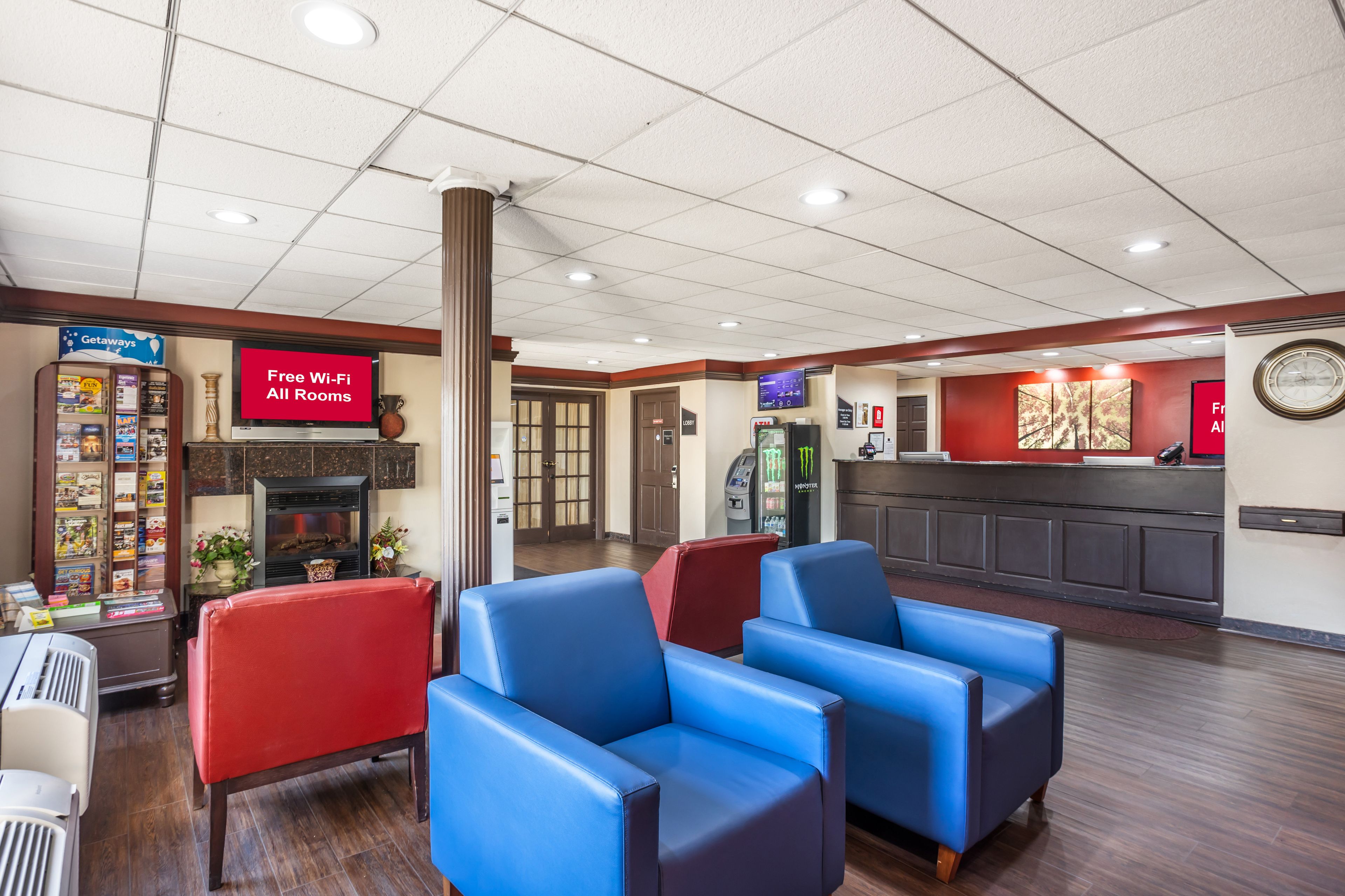 A lobby with blue and red seating, a fireplace, a Getaways sign, and a Free Wi-Fi sign.