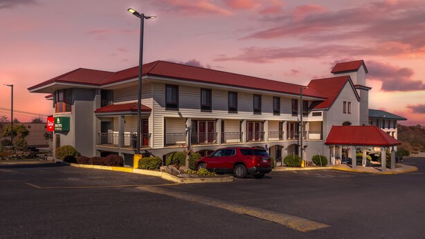 Motel amb teulada vermella, diversos balcons i un aparcament.