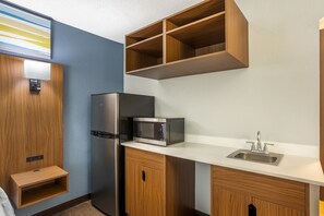 Cocina compacta con refrigerador, microondas y lavamanos.