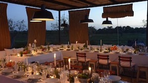 An outdoor dining area with tables set for a meal, surrounded by chairs and under hanging lights. - Pensão Agrícola (Tavira)